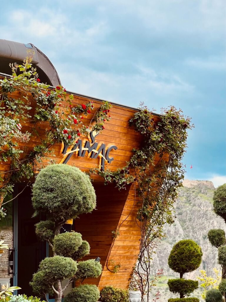 Yamaç Bistro'nun girişi, ahşap cephe üzerinde logo ve çiçeklerle süslenmiş